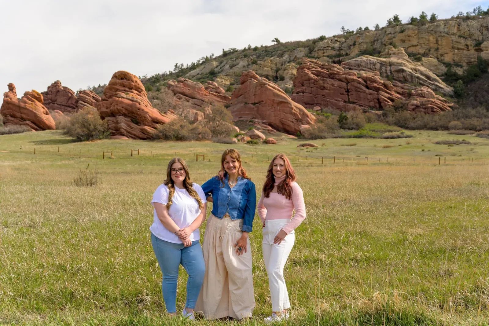 Three Recover at Home coaches in a meadow below the red rocks near Denver