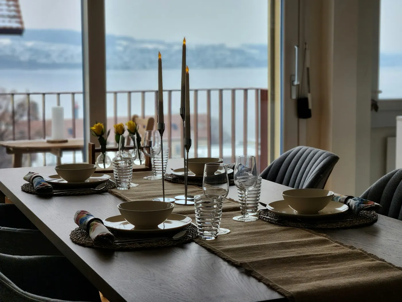 A dining table set for dinner with bowls, glasses and candles